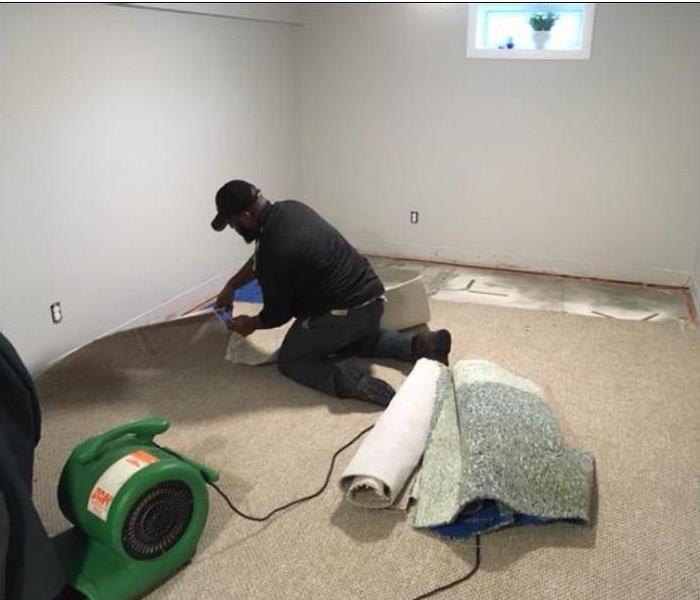 SERVPRO tech removing water damaged carpet from room.