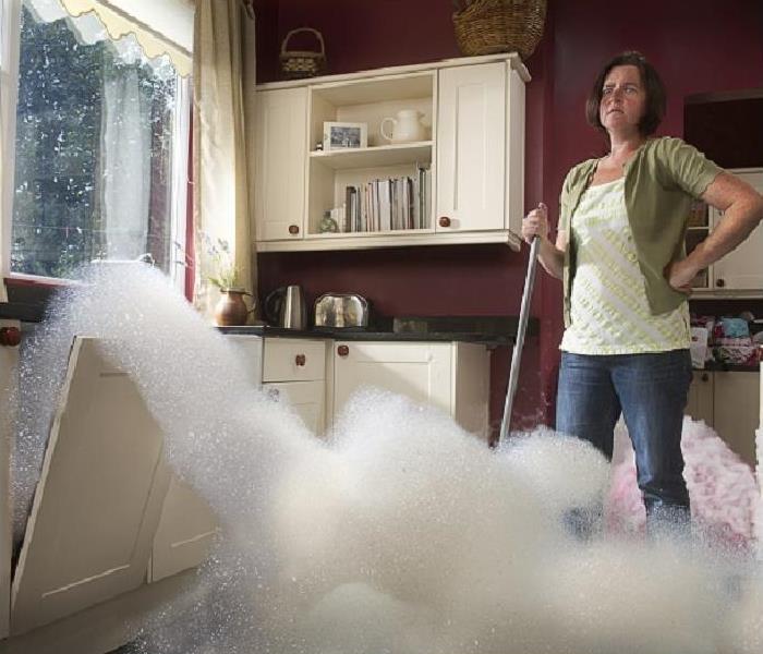 Woman watching suds overflowing from dishwasher