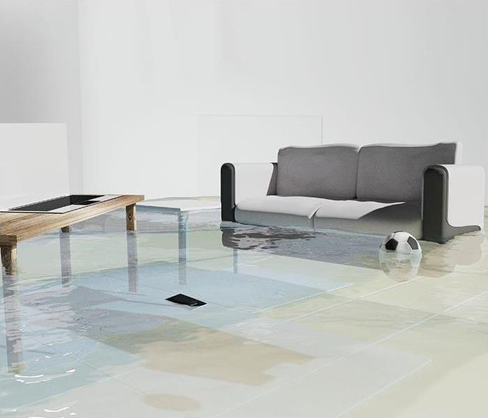 Living room with a grey couch and coffee table floating in pooling water 