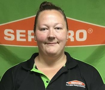 female grinning in front of a SERVPRO banner