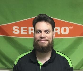 male employee with beard in front of banner